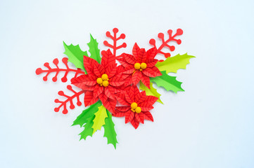 Paper flower poinsettia and leaves of holly