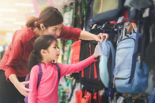 Back to school concept, Young asian mother or parent and little girl kid or cute pupil buying school satchel or bag in store, Selective focus
