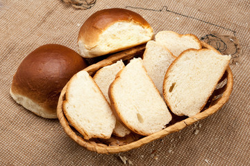 White rustic bread in wicker basket on a coarse tablecloth