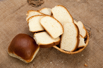 White rustic bread in wicker basket on a coarse tablecloth
