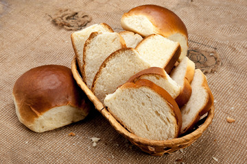White rustic bread in wicker basket on a coarse tablecloth