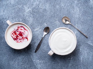 Two greek yogurt in white bowl on grey blue concrete stone table, top view