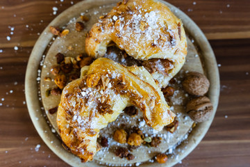 Mandelhörnchen mit Puderzucker und Nüssen auf einem Holzbrett