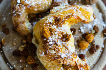 Mandelhörnchen mit Puderzucker und Nüssen auf einem Holzbrett