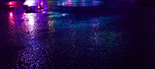 Fototapeta premium Tło mokry asfalt z neonowym światłem. Niewyraźne tło, nocne światła wielkiego miasta, odbicie, kałuże. Ciemny neon bokeh.