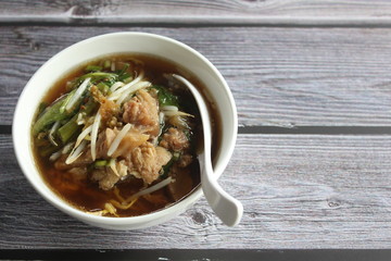 Stewed beef soup in a bowl on wooden table.