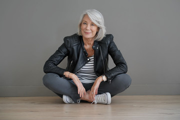  Modern senior woman sitting indoors with leather jacket