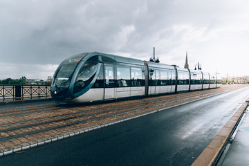 Fototapeta na wymiar Modern city tram crossing bridge after rain