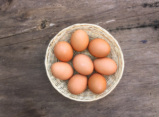 Many eggs are in a basket placed on a wooden floor.   