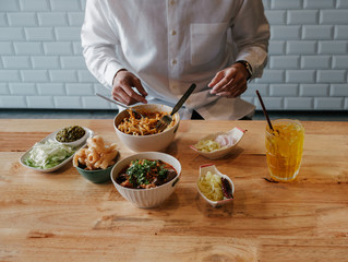 Asian Man eat  Thai Food -Khao Soi with pork snack (Thai Noodle Curry Soup with chicken), Nam Prik Num (Green chili dip) and  Hunglei curry (North curry With tender pork) over the wooden table