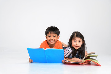 a group of Cute little asian boy and girl reading book while sitting or lying over white background