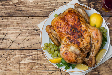Baked chicken, wine glasses and fruit for dinner on the festive table. copy space