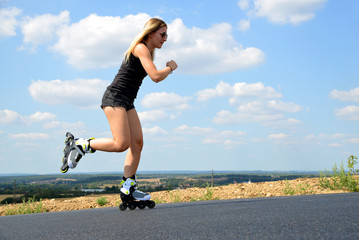 Teenage girl on roller skates at summer. Inline skating on the road.