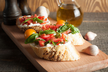 Italian tomato and cheese bruschetta. Tapas, antipasti with chopped vegetables, herbs and oil on grilled ciabatta and baguette bread.