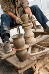 The hands of a potter forms on pottery wheel clay pot