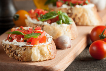 Fototapeta na wymiar Italian tomato and cheese bruschetta. Tapas, antipasti with chopped vegetables, herbs and oil on grilled ciabatta and baguette bread.