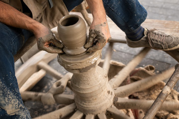 Potter hands makes on the pottery wheel clay pot