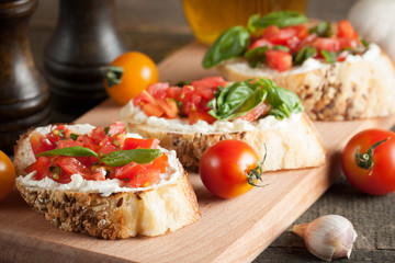 Italian tomato and cheese bruschetta. Tapas, antipasti with chopped vegetables, herbs and oil on grilled ciabatta and baguette bread.