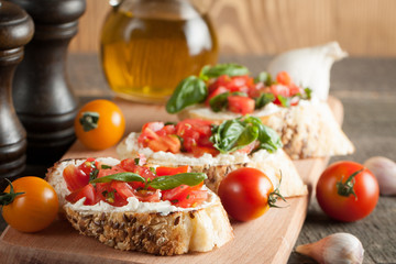 Italian tomato and cheese bruschetta. Tapas, antipasti with chopped vegetables, herbs and oil on grilled ciabatta and baguette bread.