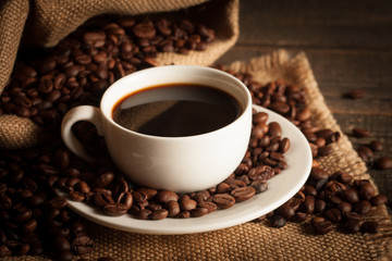 Coffee cup and beans on a rustic background. Coffee Espresso and a piece of cake with a curl. Cup of Coffee and coffee beans on table.