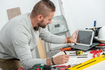 young man using a tablet to tinker at home