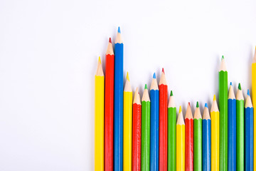 Many different colored pencils on a white background with a place for text and cory space .