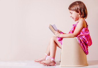 Toilet busy Images. Little cute child girl with notebook sitting on toilet bowl. - obrazy, fototapety, plakaty