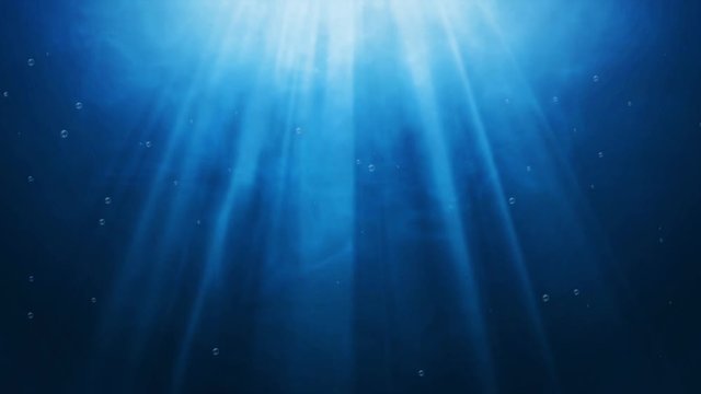 Dark blue ocean surface seen from underwater and rays of sunlight shining through