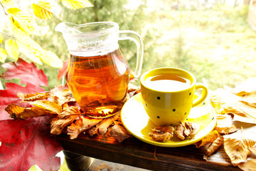 Hot tea and autumn leaves on vintage wood background. Warm sunny day of the golden autumn 