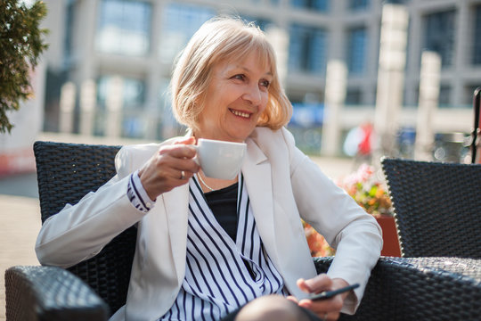 Senior businesswoman is having coffee break in cafe.