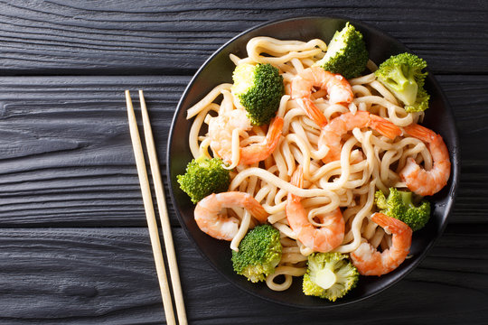 Udon noodles with shrimps and broccoli closeup on a plate. horizontal top view