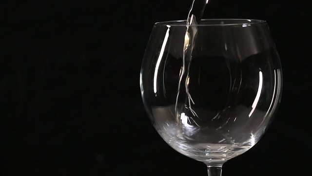 Pouring white wine into glass. Slow motion