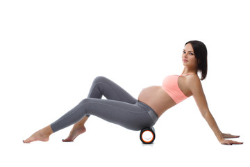 Fototapeta na wymiar Slim pregnant woman performs exercises with massage roller isolated on white background.