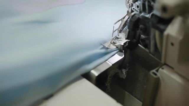 Woman's hands sewing an overlock at sewing machine. Overlock stitch on sewing machine. Automatic sewing machine. Close-up