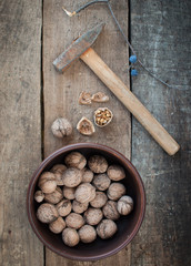 Walnut in bowl on wooden background and hammer