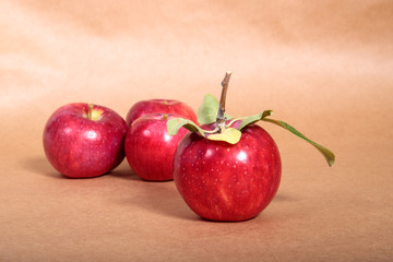 Red apples with green foliage lie on a light background. Space for text.