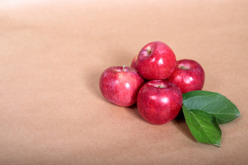 Red apples with green foliage lie on a light background. Space for text.
