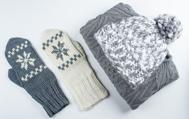 Collection of woolen winter clothes - knitted sweater, mittens, hat on white background table. Top view, flat lay