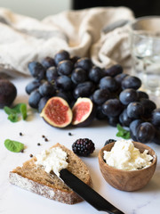 Rye bread and a knife with cream cheese and various fruits on a marble background. Cooking toast with cheese and berries.