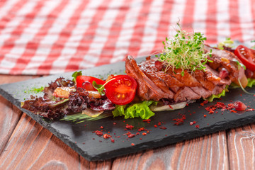 Tasty sliced roast duck breast with fresh vegetable salad closeup on a plate.