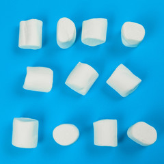 marshmallow laid out on blue paper background. pastel creative textured pattern.