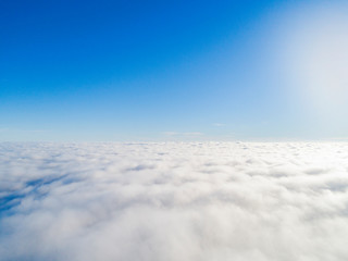 Aerial view White clouds in blue sky. Top view. View from drone. Aerial bird's eye view. Aerial top view cloudscape. Texture of clouds. View from above. Sunrise over clouds