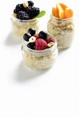 Oat flakes with various berries, hazelnuts and honey in glass jars, vertical, copy space