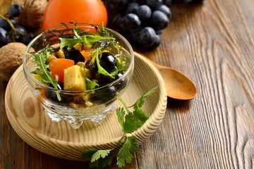 Delicious salad with persimmons, arugula, grapes and cheese, sprinkled with walnuts, copy space