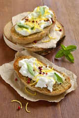 Lemon, basil, pink pepper, ricotta and honey bruschetta, vertical 
