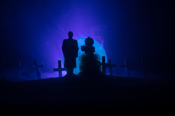 Fototapeta premium Halloween. Scary zombie bride on a night cemetery holds a pumpkin lantern.