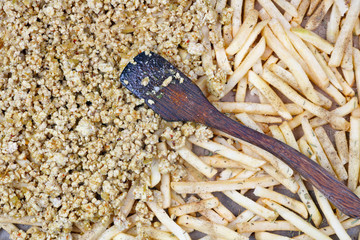 The  strips of potatoes  and minced pork  on a baking sheet sprinkled with salt pepper and  herbs spices