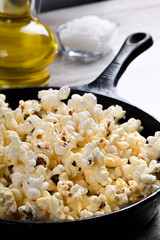  Prepared popcorn in frying pan, corn seeds in bowl and corncobs on kitchen table.Air salty popcorn. Salt popcorn on the wooden background . Chees .Popcorn texture
