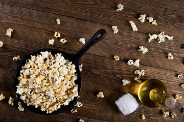  Prepared popcorn in frying pan, corn seeds in bowl and corncobs on kitchen table.Air salty popcorn. Salt popcorn on the wooden background . Chees .Popcorn texture