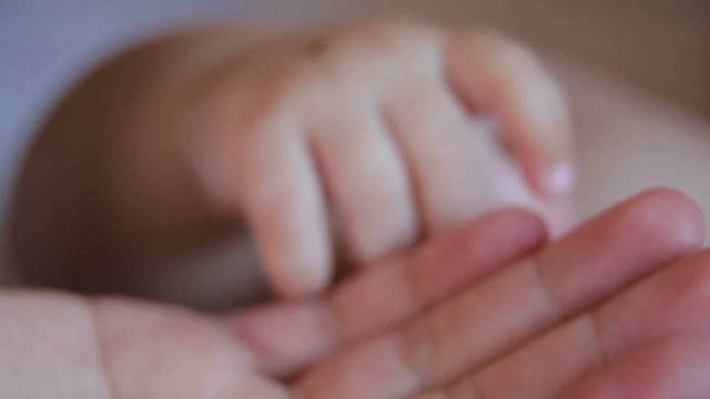 Close-up of the hand of a newborn baby in the hand of the mother, mom is playing with the hands of a newborn baby. Birthmark on the hand of a newborn child.